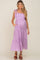 woman wearing a purple gingham maternity maxi dress with tie straps and pockets, showcasing her baby bump