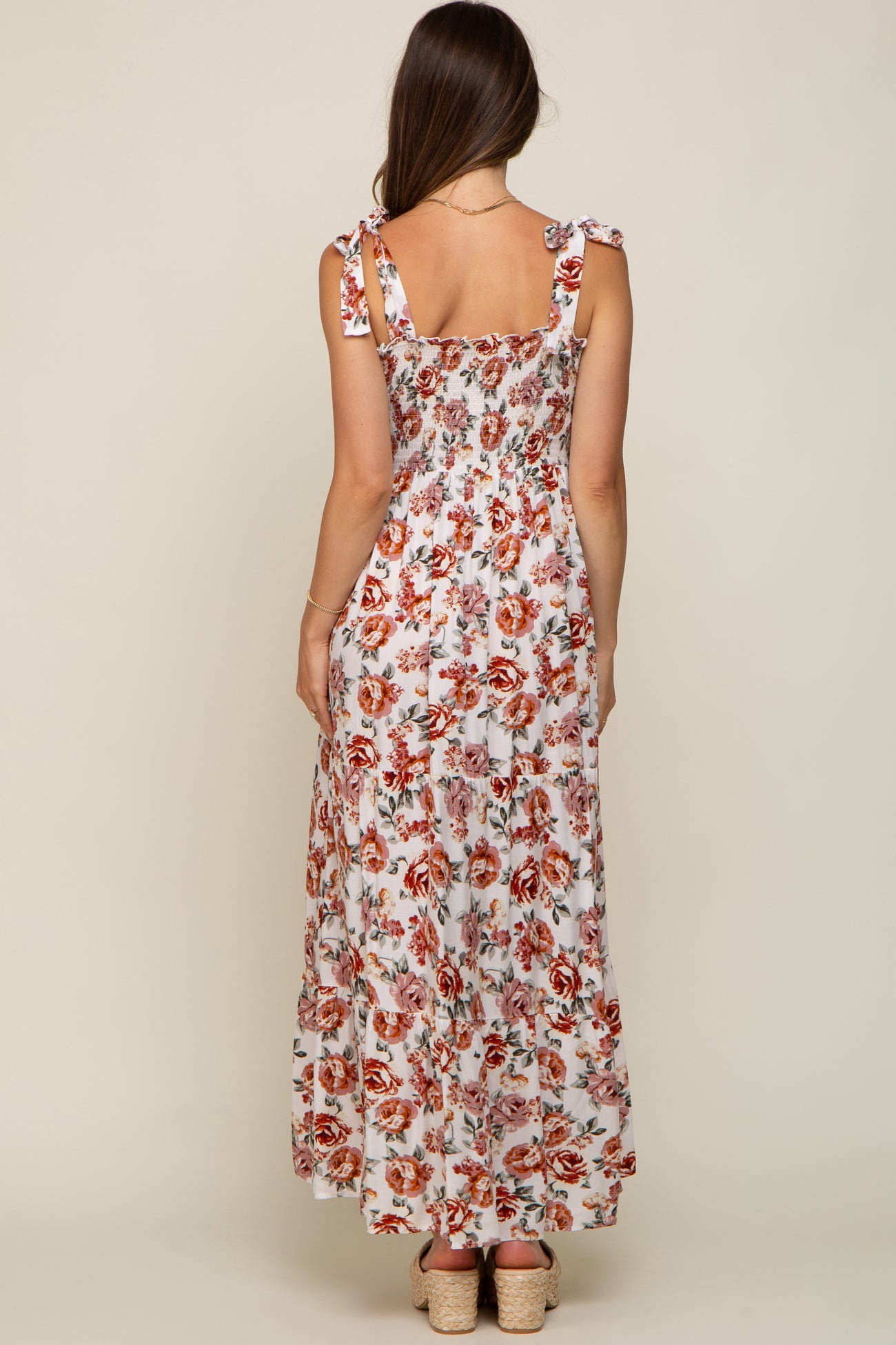 woman wearing a floral maternity maxi dress with tie straps, featuring a smocked back design