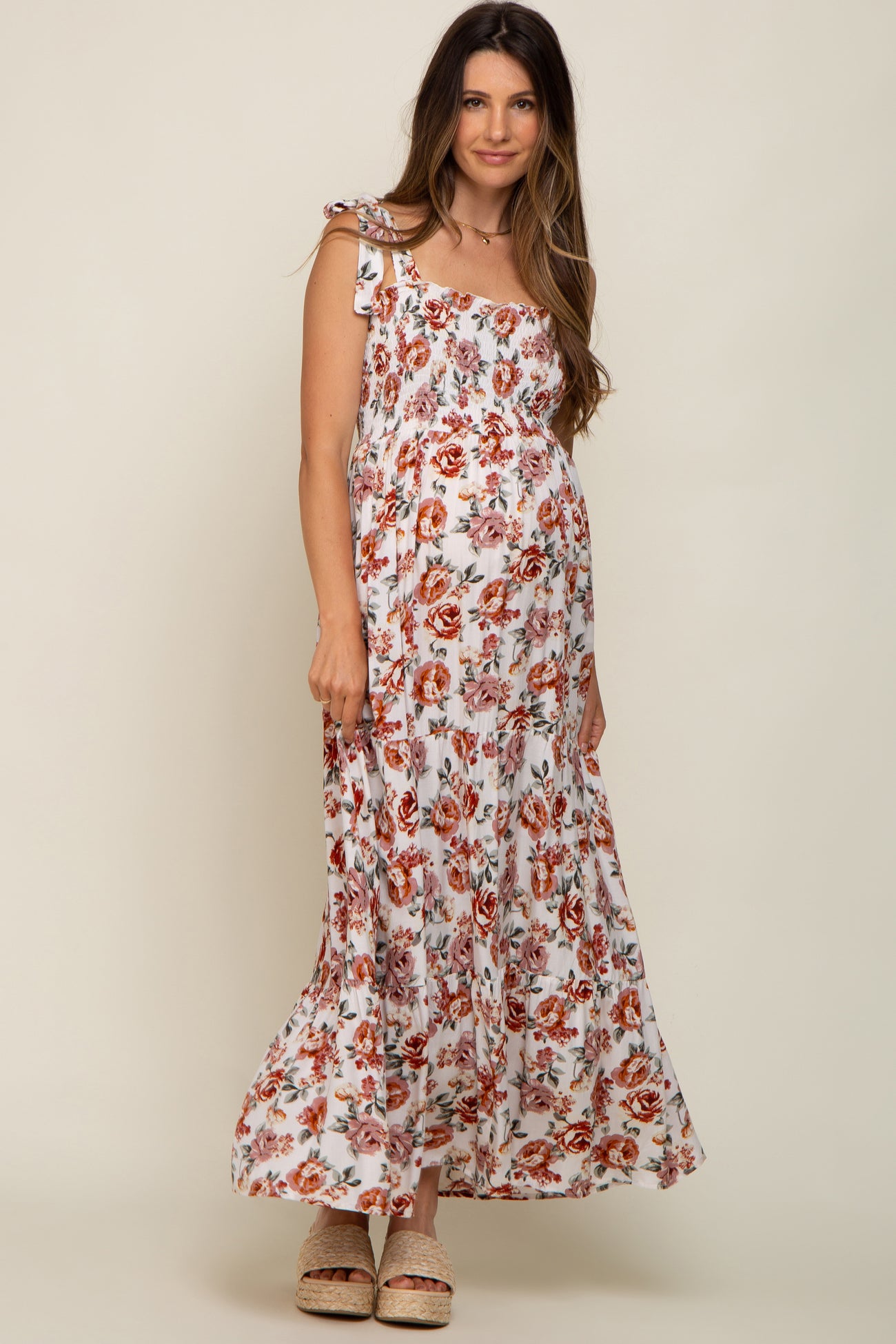 woman wearing a floral maternity maxi dress with off-the-shoulder straps and a baby bump visible
