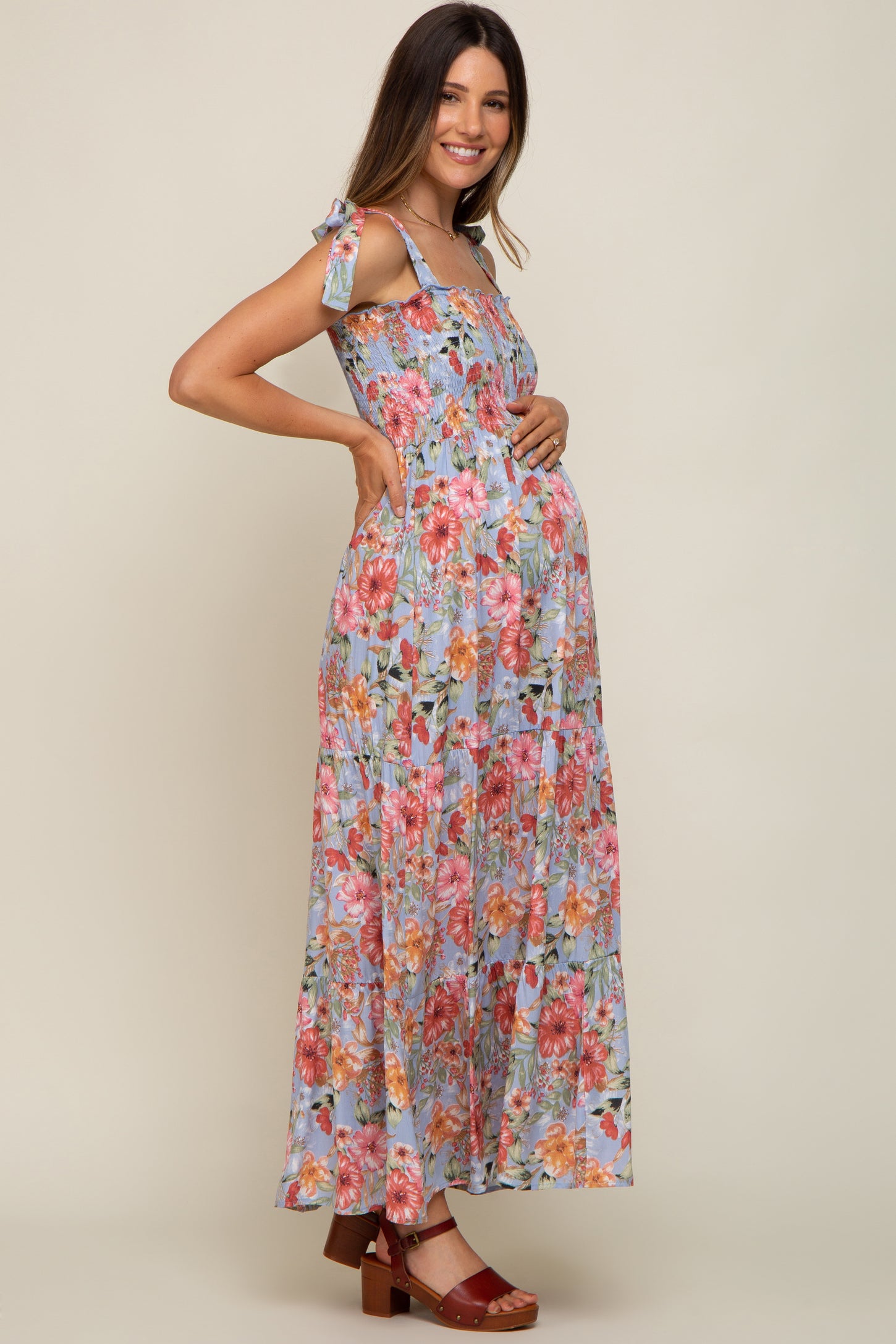 woman wearing a floral maxi maternity dress with adjustable tie straps and a visible baby bump