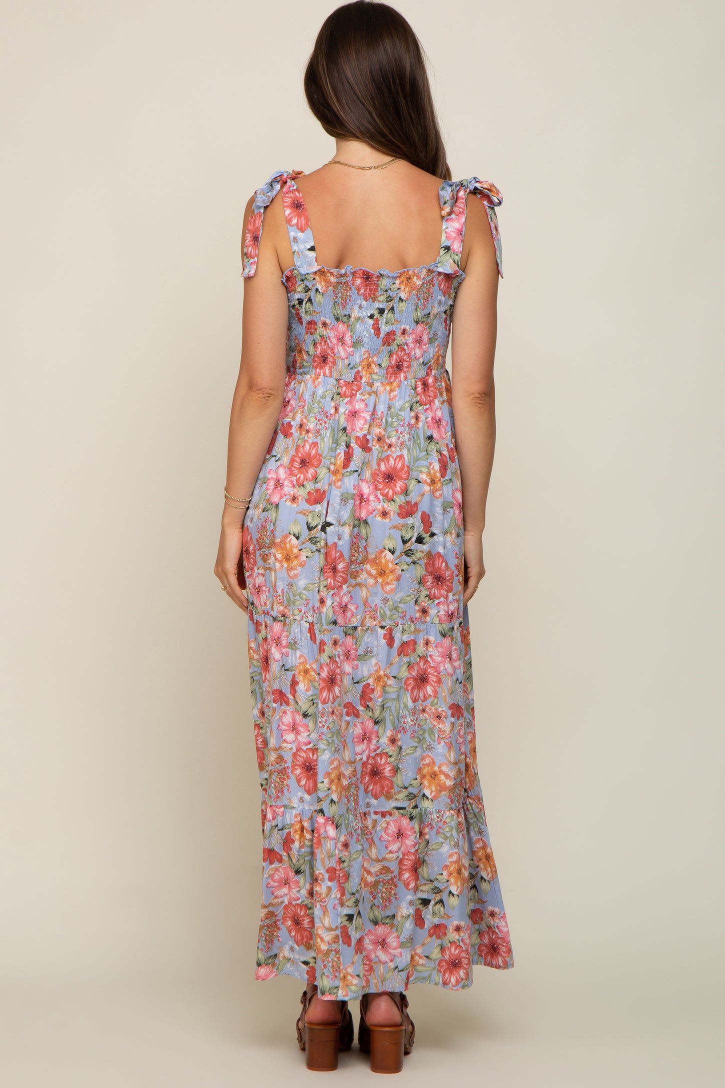 woman wearing a floral print maternity maxi dress with tie straps and a smocked back