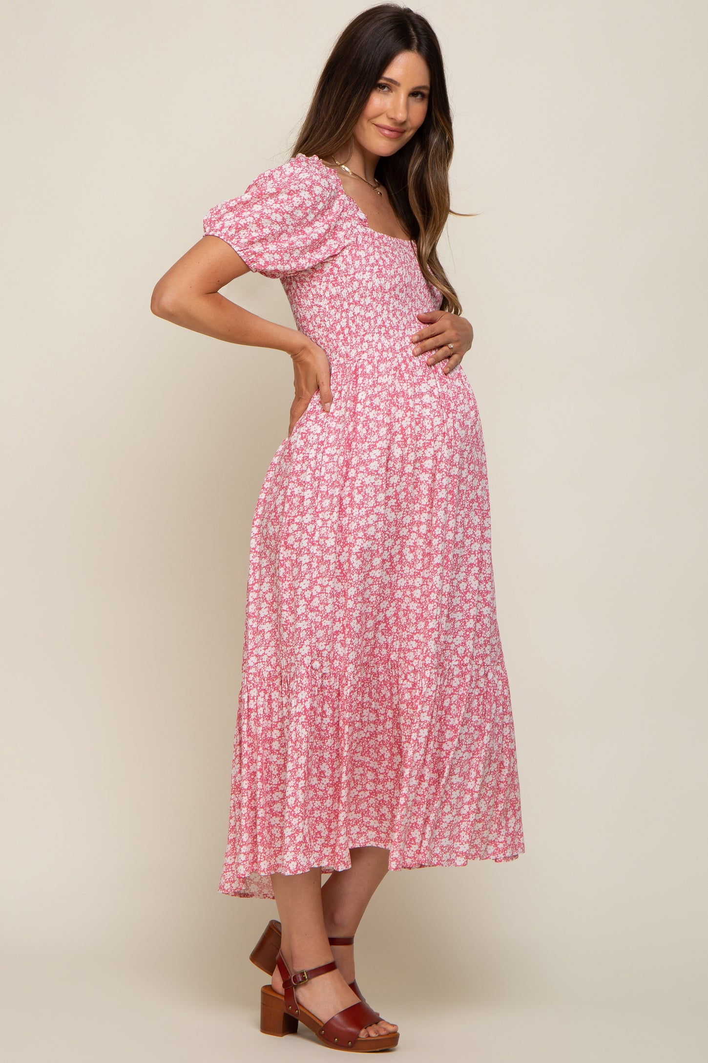 woman wearing a pink floral maternity dress with short puff sleeves and a baby bump