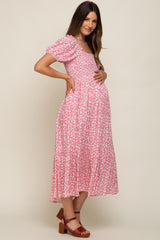 woman wearing a pink floral maternity dress with short puff sleeves and a baby bump