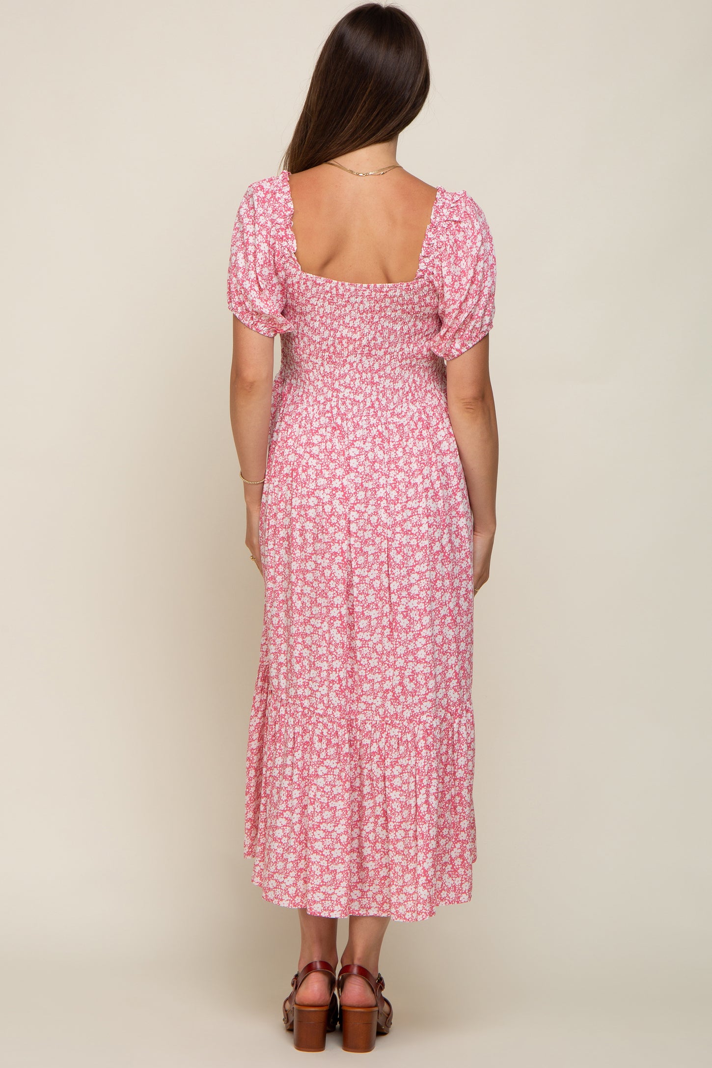 woman wearing a pink floral maternity maxi dress with puff sleeves and a tiered skirt, showing a baby bump