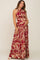 woman wearing a burgundy floral halter neck maternity maxi dress and cradling her baby bump