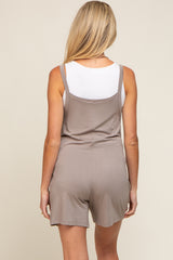 woman wearing a taupe maternity romper with adjustable straps and a relaxed fit, showing the back view