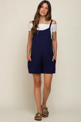 woman wearing a navy blue maternity romper with off-shoulder top and pockets, showcasing a baby bump