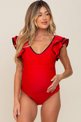 woman wearing a red ruffled maternity swimsuit with a v-neckline and a visible baby bump