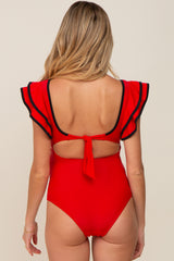 woman wearing a red maternity swimsuit with ruffled sleeves and a tie back detail