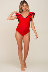 woman wearing a red maternity one-piece swimsuit with ruffled sleeves and a v-neckline, showing a baby bump