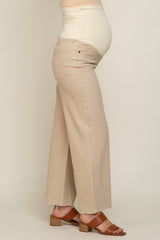 woman wearing a beige maternity pant with a stretchy belly panel, showing her baby bump, paired with brown block-heeled sandals
