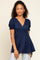 woman wearing a navy blue short sleeve peplum top with a v-neck and smocked puff sleeves