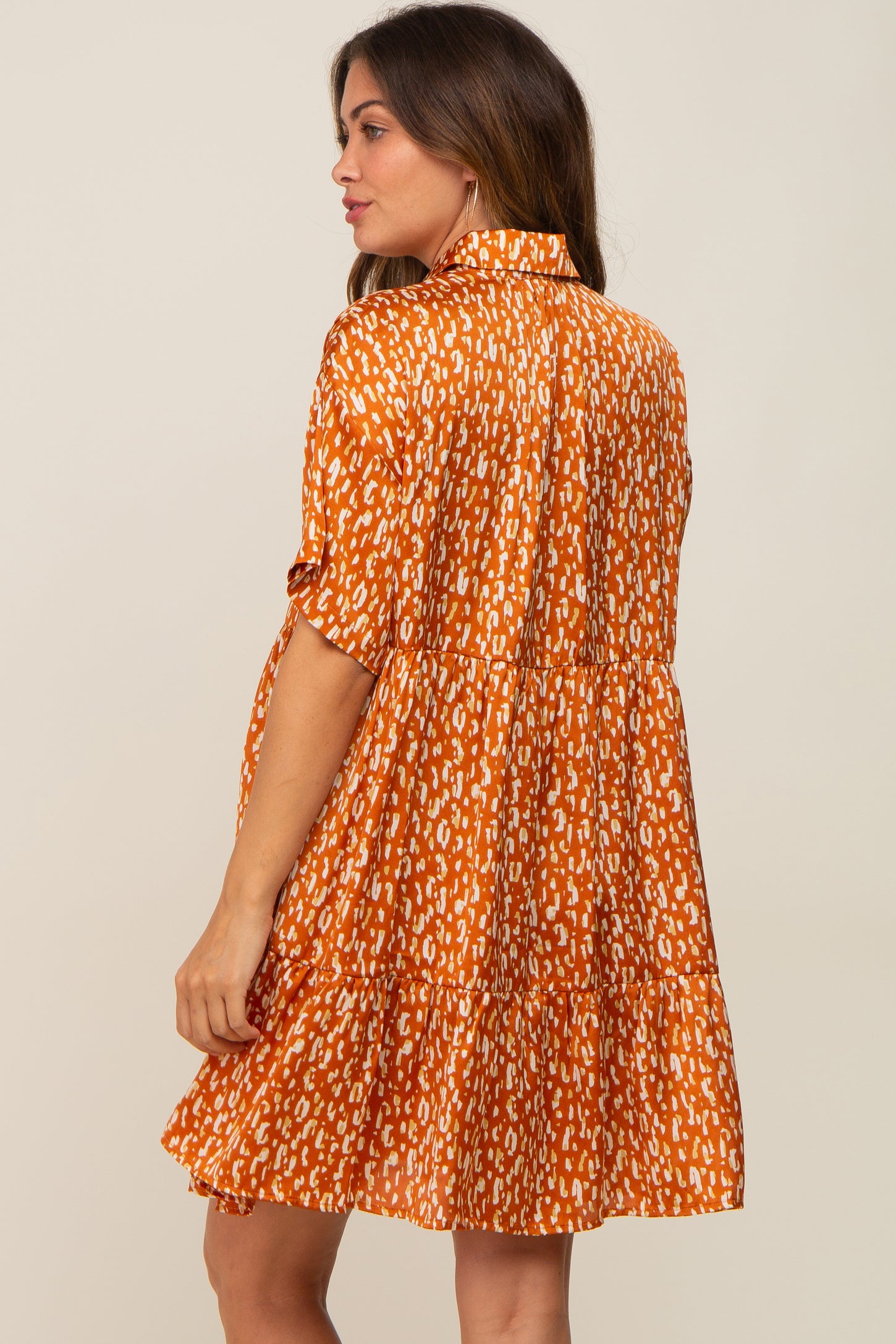 woman wearing an orange maternity dress with a tiered skirt and a patterned design, showing a baby bump from the side