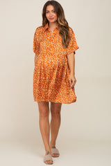 woman wearing an orange patterned short sleeve maternity dress with a relaxed fit and pockets, showing her baby bump