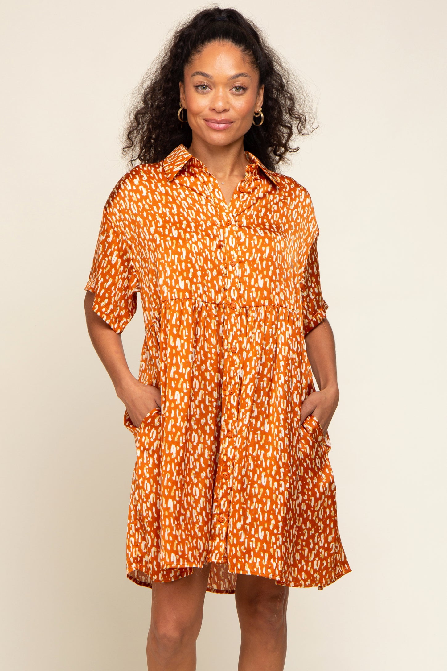 woman wearing an orange short sleeve button-up dress with a relaxed fit and front pockets