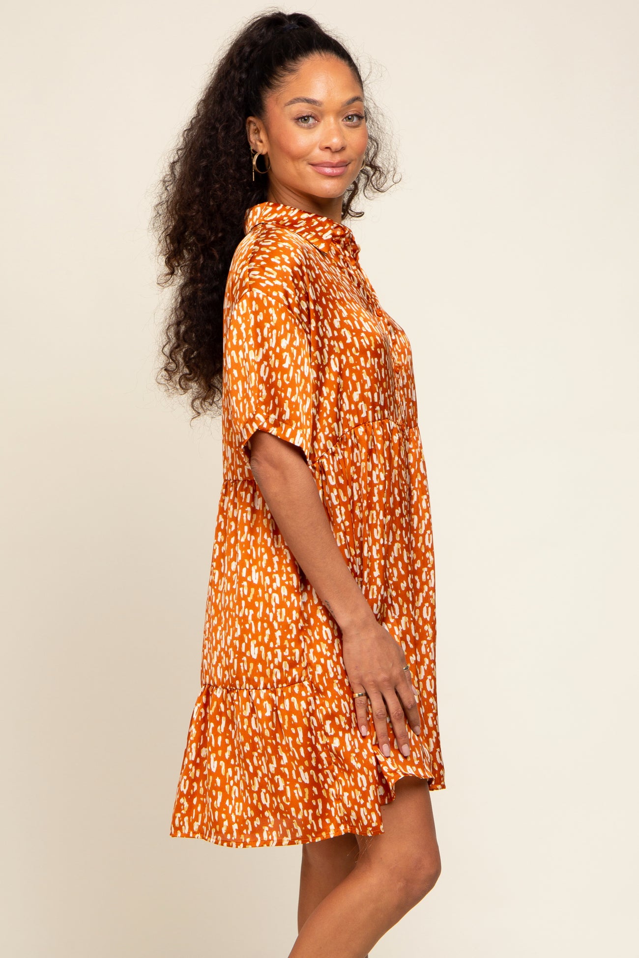 woman wearing an orange short sleeve patterned dress with a tiered skirt and collared neckline