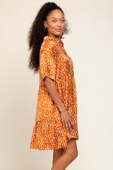 woman wearing an orange short sleeve patterned dress with a tiered skirt and collared neckline