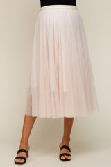 woman wearing a flowy light pink tulle maternity skirt with an elastic waistband and layered design
