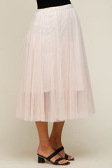 woman wearing a light pink tulle maternity skirt with a flowy design and black heeled sandals