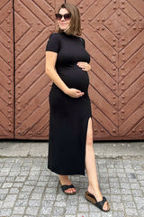 woman wearing a black short sleeve maternity dress with a side slit and a visible baby bump