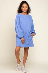 woman wearing a loose-fitting light blue sweatshirt dress with long sleeves and paired with white sneakers