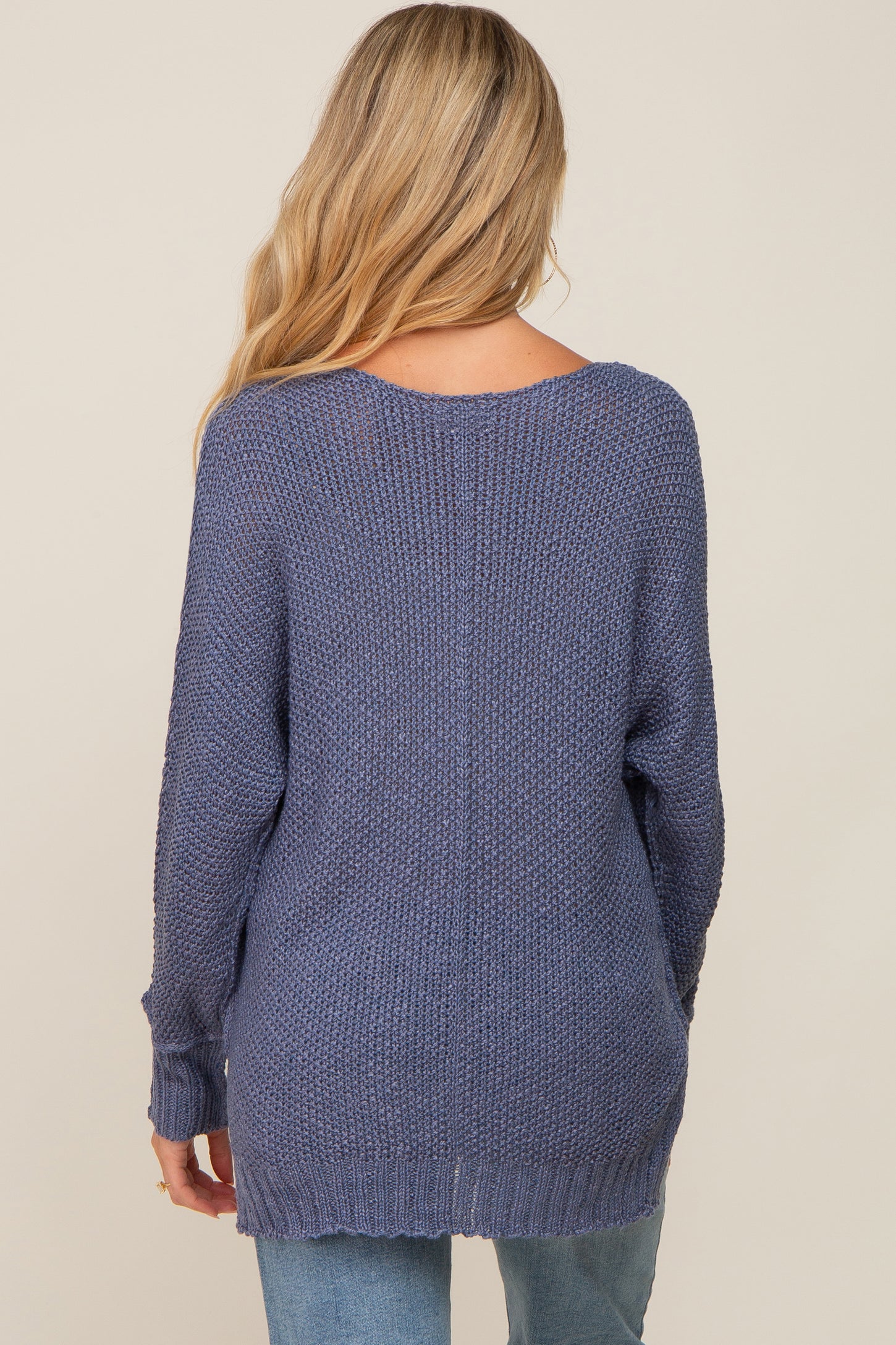 woman wearing a long sleeve navy maternity sweater, showing the back view and relaxed fit