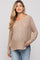 woman wearing a beige knitted maternity sweater with a v-neck and relaxed fit, styled with light blue jeans