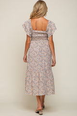 woman wearing a floral print maternity dress with ruffled sleeves and a tiered skirt, showing her back