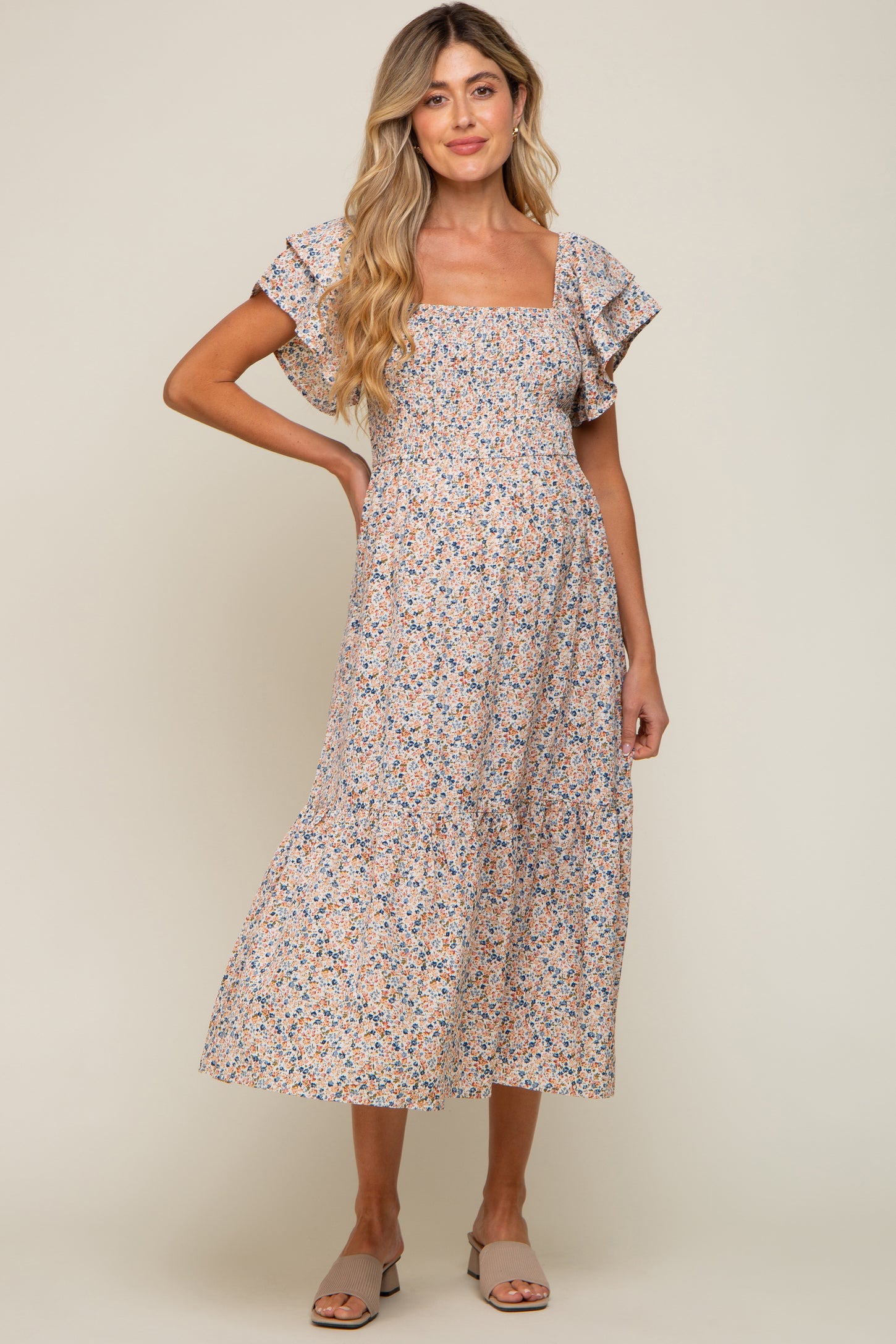 woman wearing a floral print maternity dress with short ruffle sleeves and a square neckline, displaying her baby bump