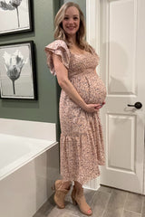 woman wearing a pink floral maternity dress with ruffle sleeves and a visible baby bump