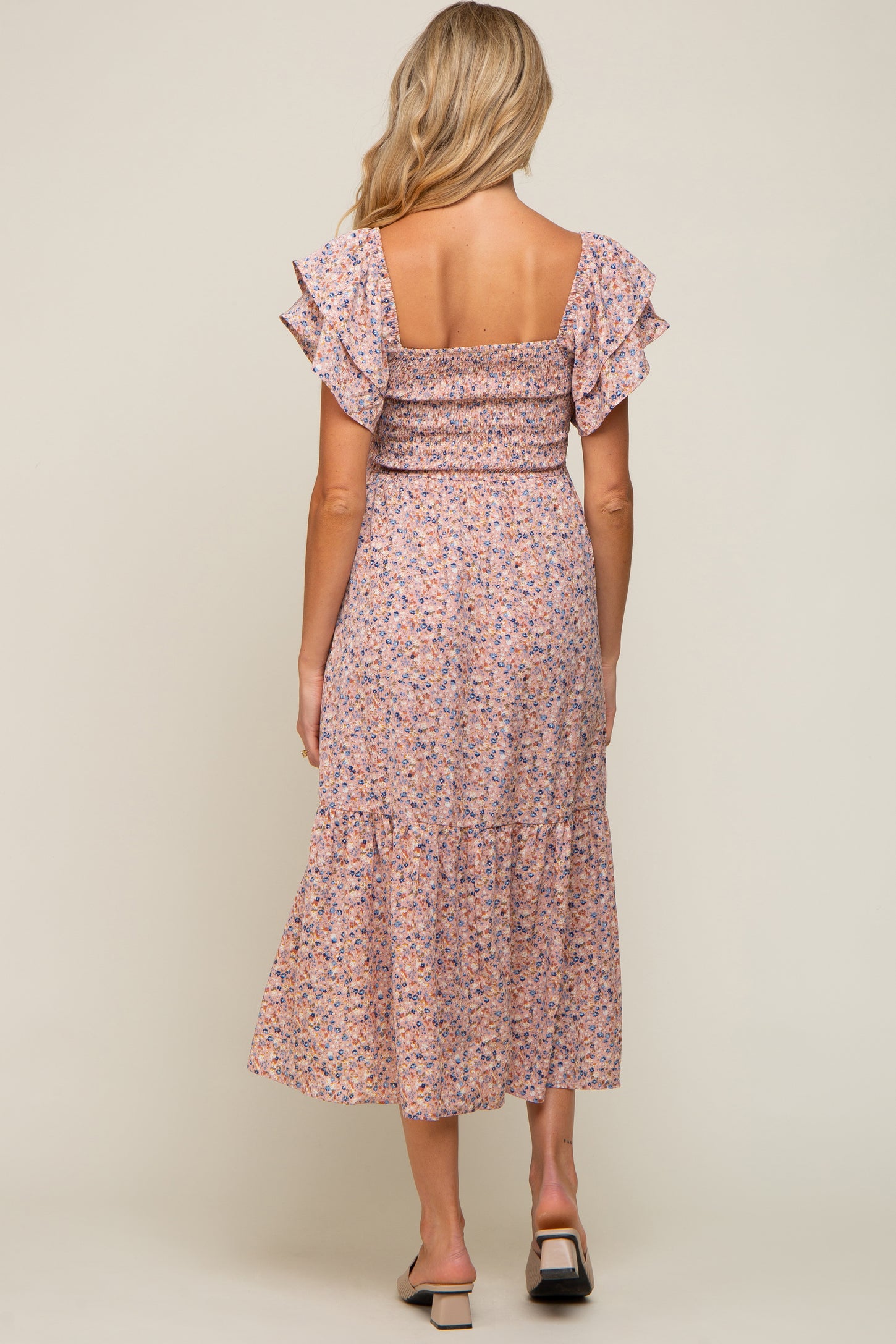woman wearing a floral maternity midi dress with ruffled sleeves and a smocked bodice, showing a side view