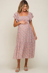 woman wearing a floral print maternity dress with ruffled sleeves and a baby bump visible