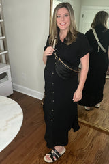 woman wearing a black maternity dress with buttons, holding a black crossbody bag, and showing a baby bump