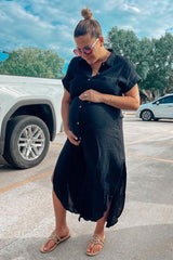 woman wearing a black linen maternity shirt dress, holding her baby bump with a scenic background