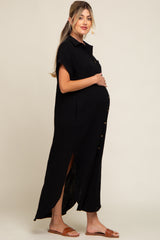 pregnant woman wearing a black short sleeve button down maternity maxi dress with side slits and brown sandals