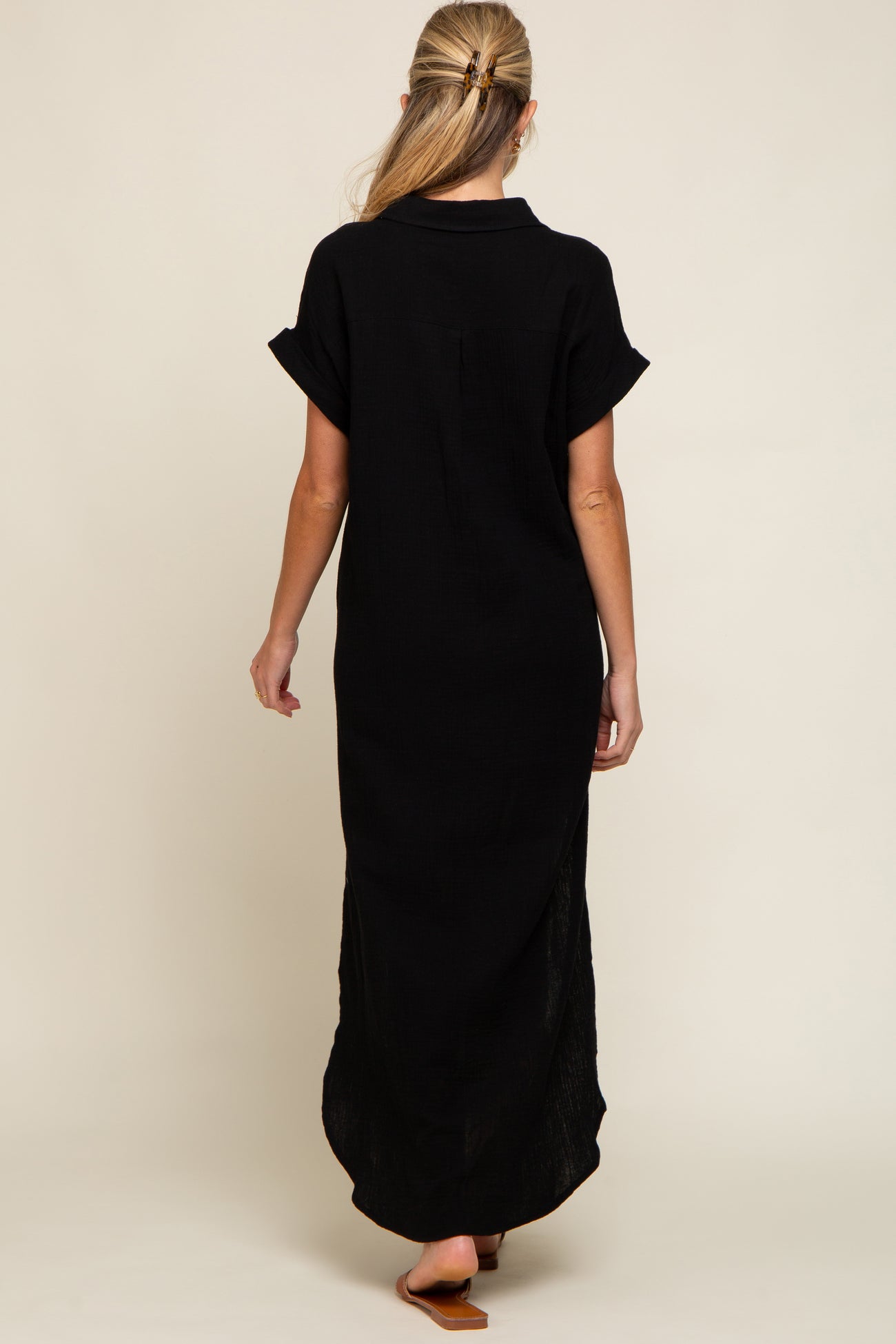 woman wearing a black maternity maxi dress with short rolled sleeves and a back slit