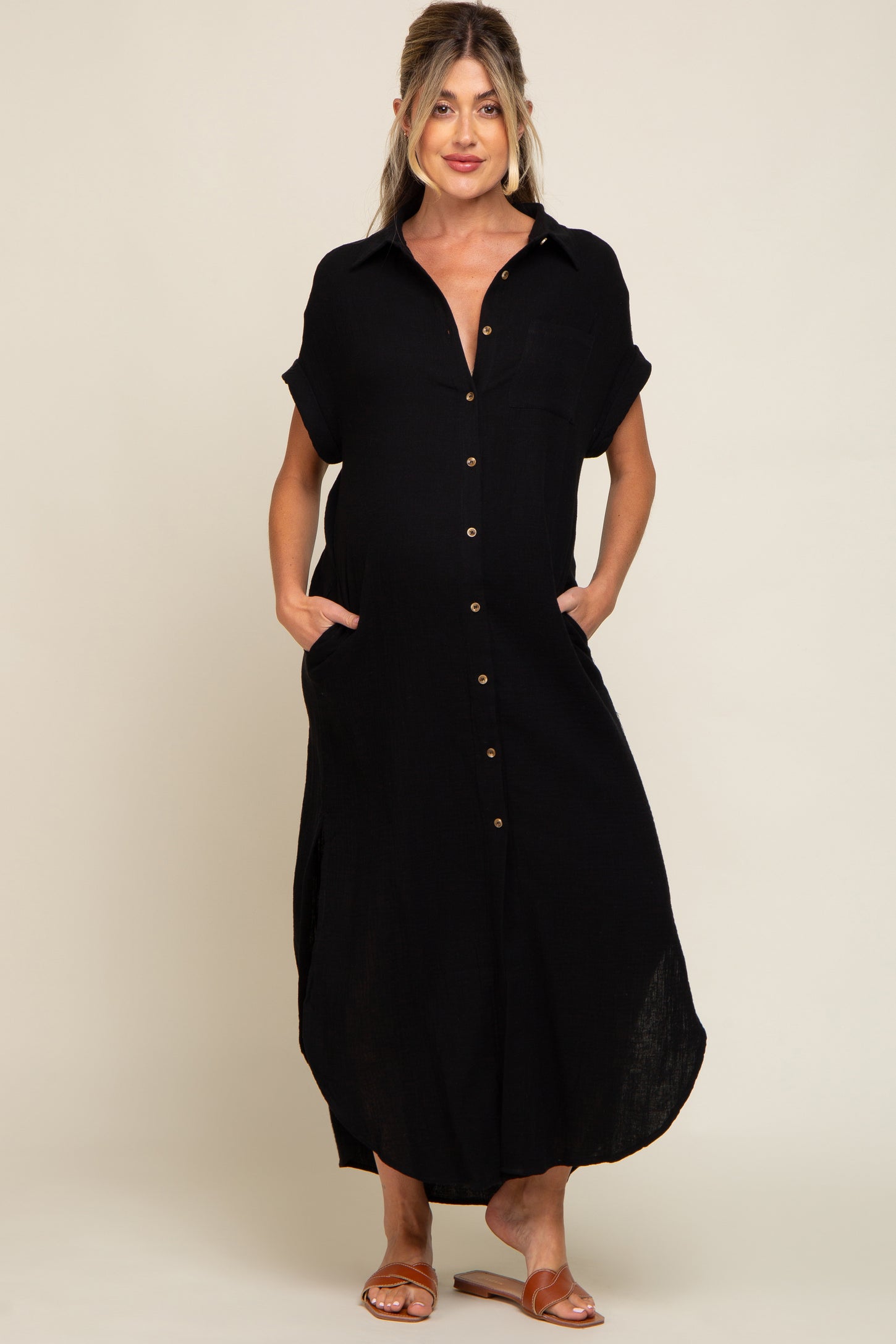 woman wearing a black button-up maternity dress with short sleeves and pockets, featuring a visible baby bump