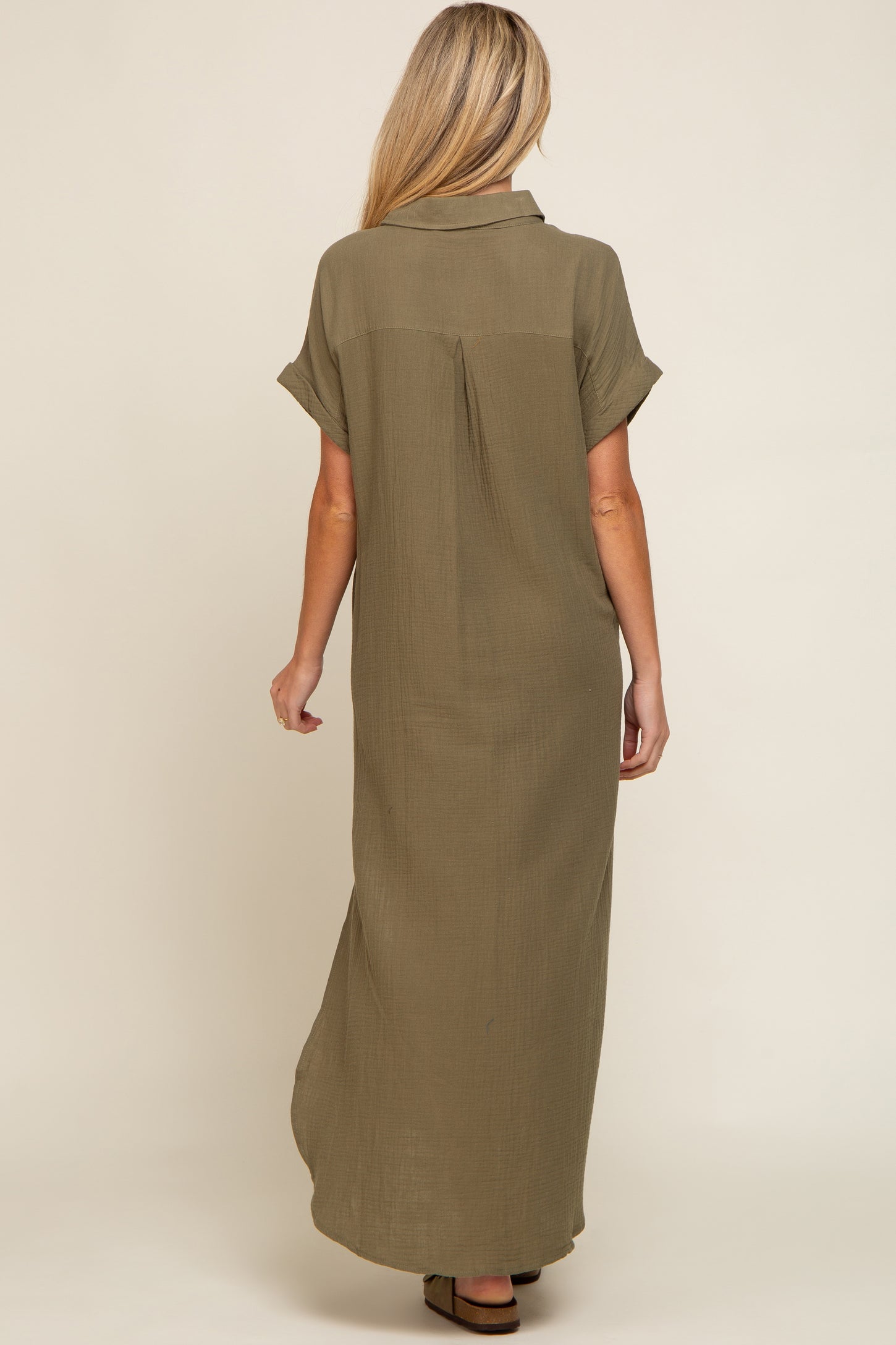 woman wearing an olive green maternity maxi dress with short sleeves and a back pleat