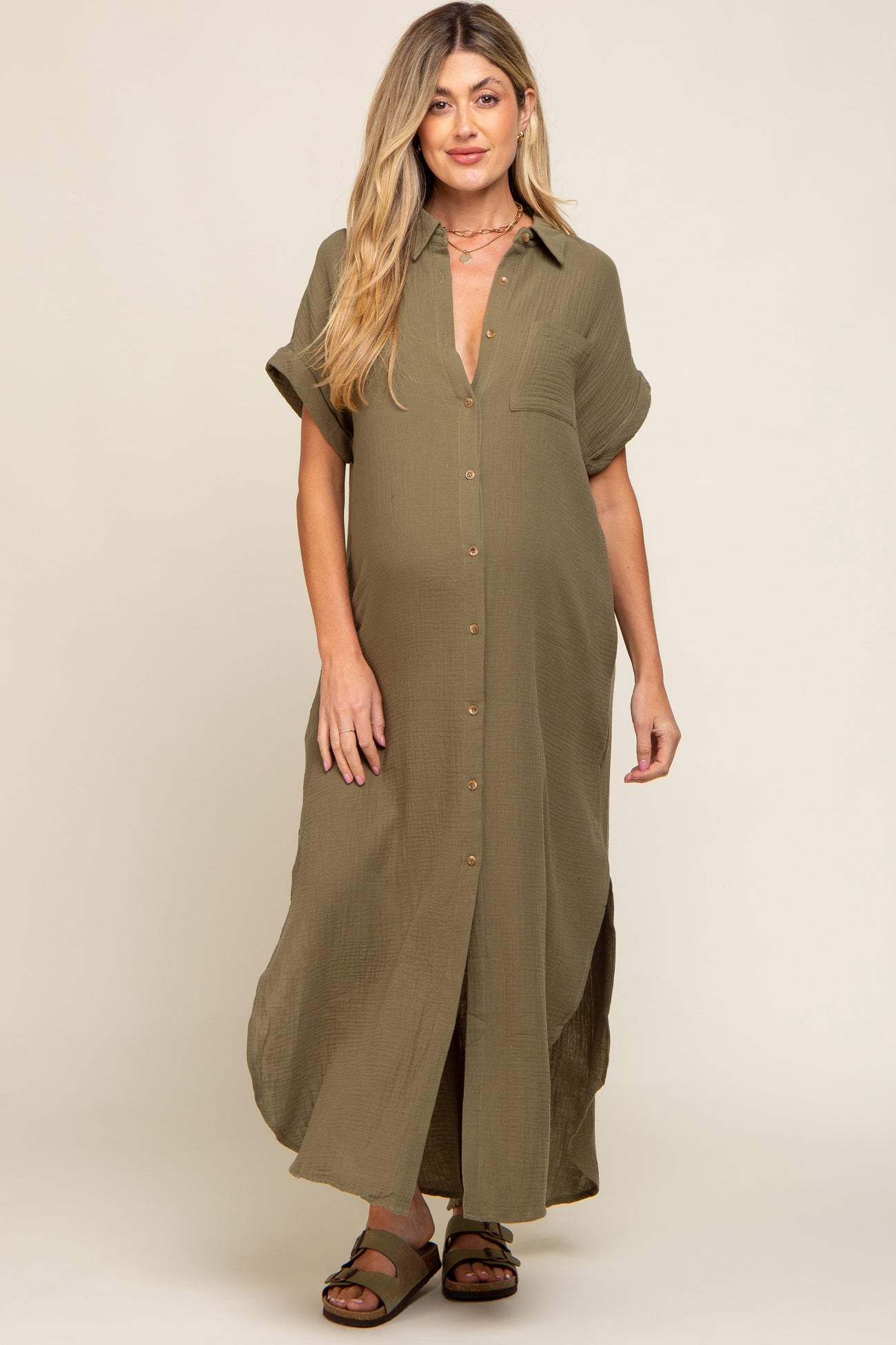 woman wearing an olive green maternity dress with short sleeves and button details, showcasing her baby bump