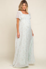 woman wearing a light green floral maternity maxi dress with puff sleeves and a smocked bodice, showing her baby bump