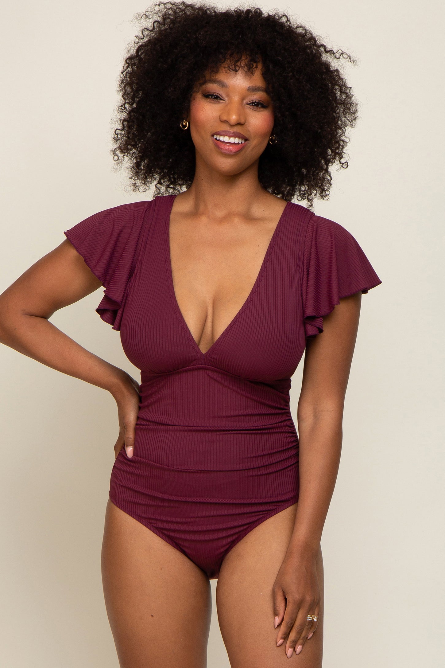 woman wearing a burgundy ruffled one-piece swimsuit with a deep v-neck and a flattering fit