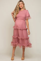 woman wearing a blush pink maternity dress with ruffled layers and short sleeves, showcasing her baby bump