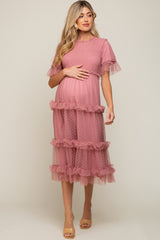 woman wearing a pink maternity dress with ruffled layers and short sleeves, showing her baby bump