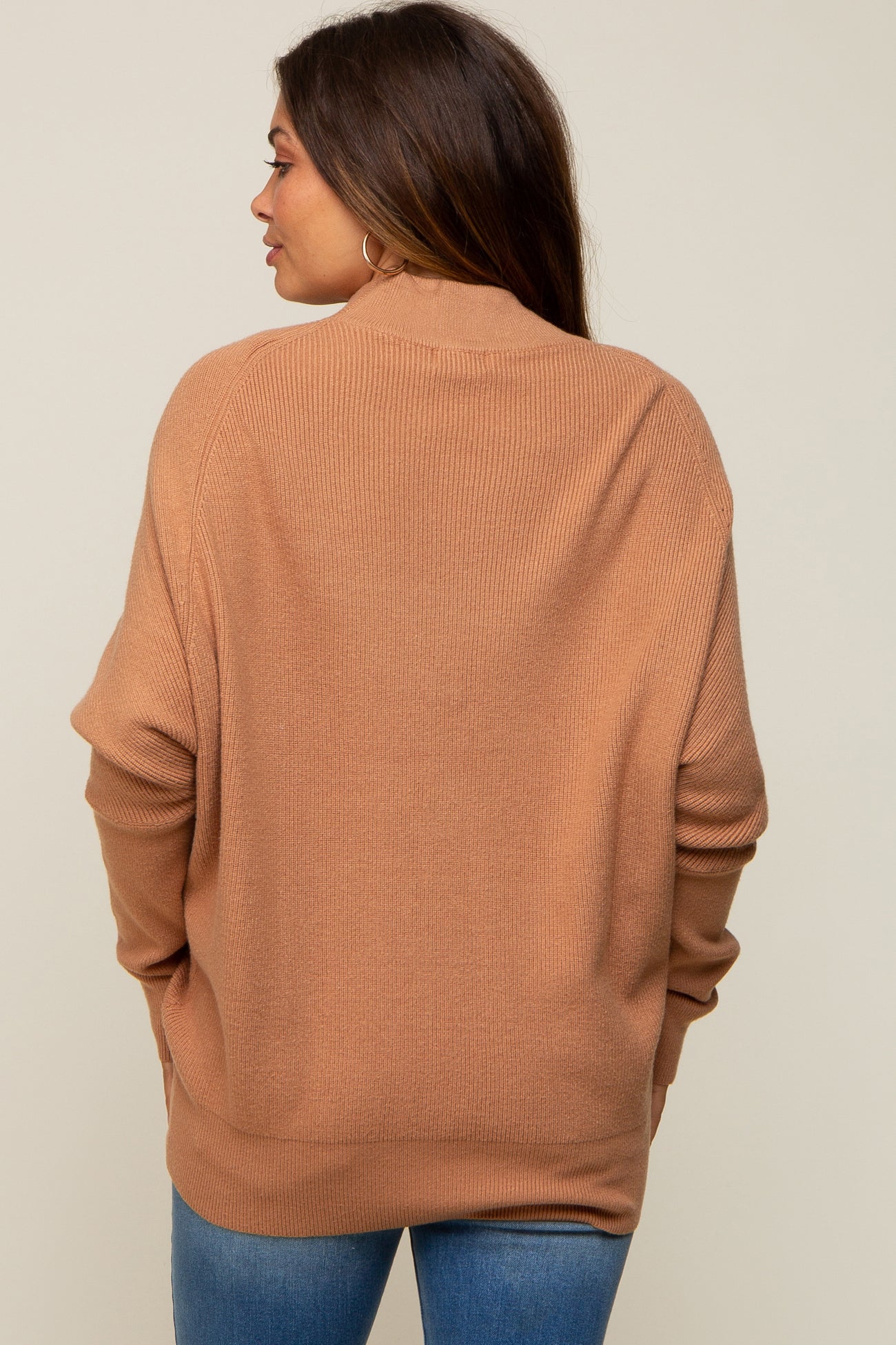 woman wearing a warm brown oversized maternity sweater, showing the back view with relaxed fit and ribbed texture