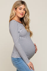woman wearing a black and white striped maternity top and showing her baby bump