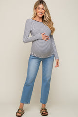 woman wearing a navy and white striped maternity long sleeve top and blue maternity jeans, showing her baby bump