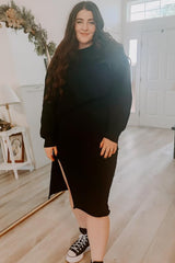 woman wearing a black long sleeve dress with a side slit and styled with black sneakers
