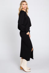 woman wearing a black long sleeve sweater and black midi skirt with side slit and beige cowboy boots
