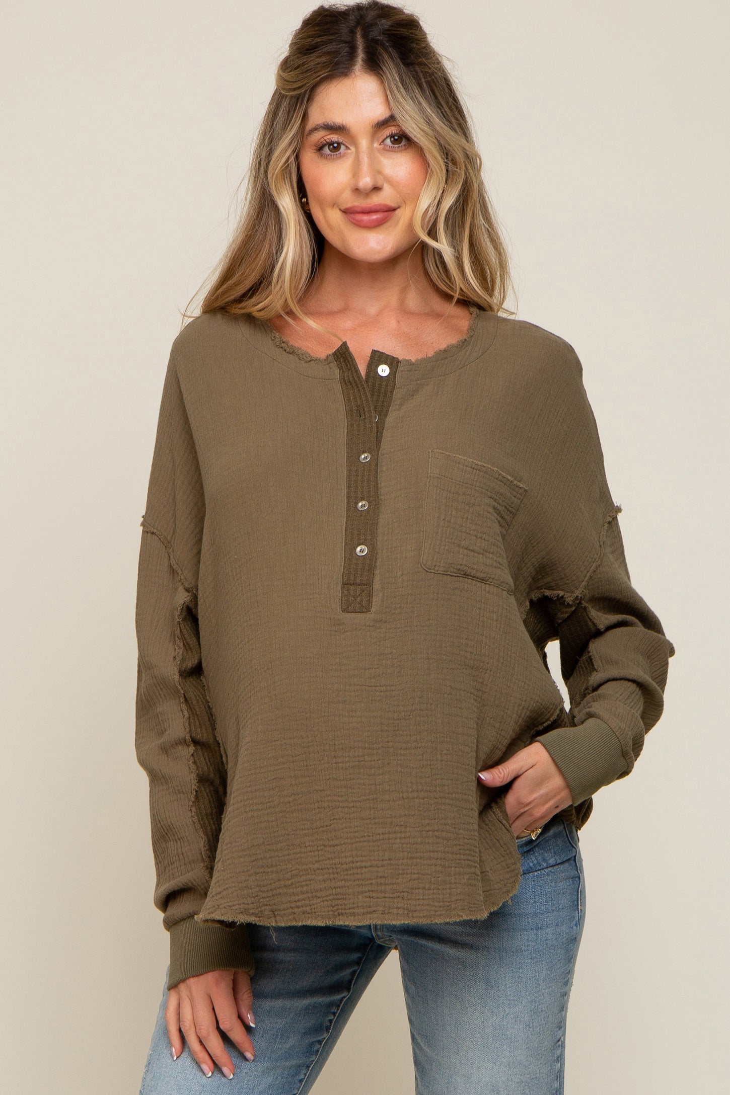 woman wearing a brown maternity top with a button placket and a front pocket, styled with blue jeans