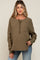 woman wearing a brown maternity top with a button placket and a front pocket, styled with blue jeans